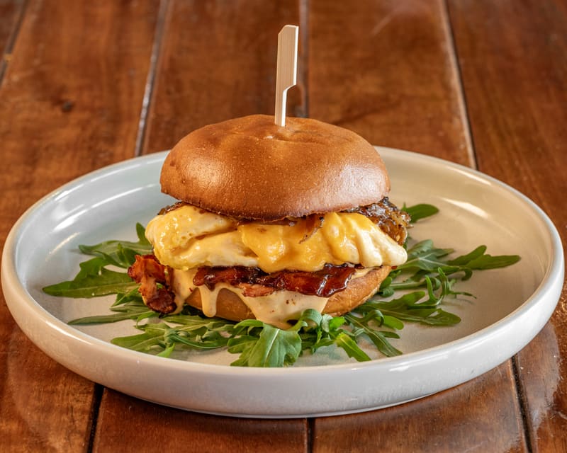 Signature bacon and egg roll with folded egg, melted cheese and Streaky Bacon on a bed of rocket
